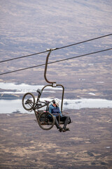 Mountain bicycle and extreme sports cyclist on a ski lift going up to a moutain sports resorts in...
