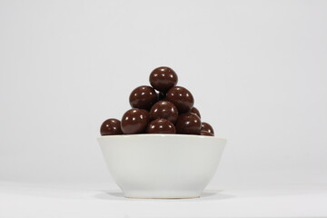 Ball-shaped chocolate candies in a white bowl. An illustration in the form of a photo to introduce a food product in the form of a ball-shaped chocolate candy.