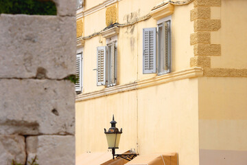 Fototapeta na wymiar Vintage cast iron street lamp and traditional Mediterranean windows. Selective focus.