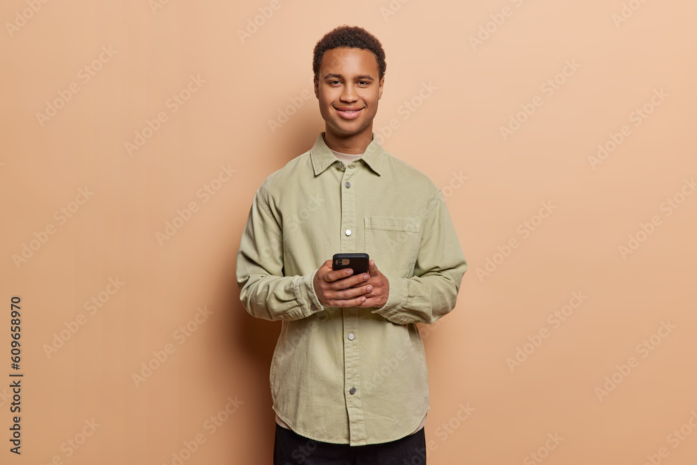 Wall mural people and technology. satisfied dark skinned man holds mobile phone enjoys communication with frien