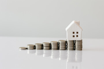 Small house and pile of coins, white background The concept of investment real estate