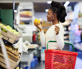 Supermarket, black woman and shopping for grocery, vegetables and customer with orange in store basket. Person, retail shop and groceries, healthy food or buying fruit for vegan diet or nutrition