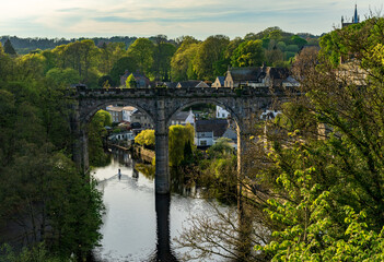 Fototapeta na wymiar Stone viaduct over River Nidd at Knaresborough with lone paddleboard on the calm surface