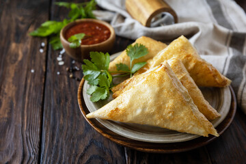 Asian food. Vegetarian samsa (samosas) with tomato sauce on a wooden table. Popular in Indonesia as Risoles Sayur. Copy space.