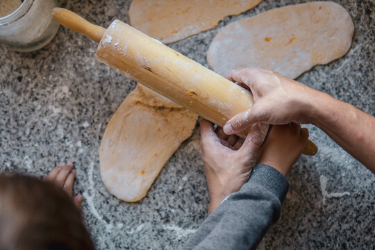 father teaching his son to cook. Father and son hands using a rolling pin