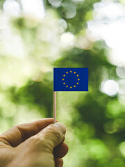 The Flag of Europe which is held in hand at the forest. - obrazy, fototapety, plakaty