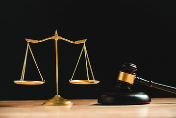 Judge gavel and scales of justice in court on black background with wooden table. Law court and...