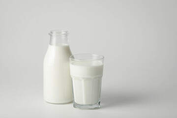 A glass and bottle of milk of milk on a white background