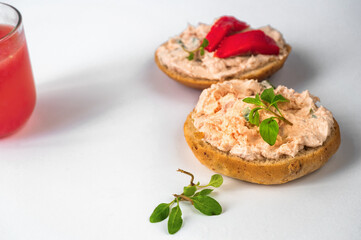 2 canapés with salmon spread and fresh cheese, leaf, part of glass of juice.