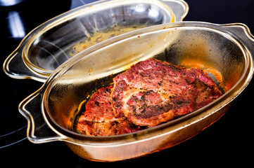 Baked marinated pork fillet in glass pan on black .