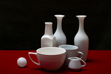 Still life with white dishes on a red table