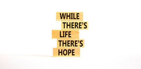 Life and hope symbol. Concept word While there is life there is hope on wooden block. Beautiful white table white background. Business lifestyle life and hope concept. Copy space.