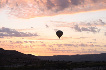 Silhouette of floating air balloon over mountain valley