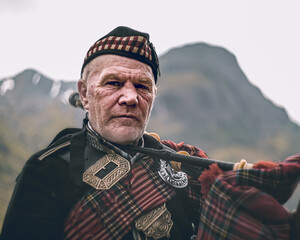 Scottish piper posing in the highlands - obrazy, fototapety, plakaty