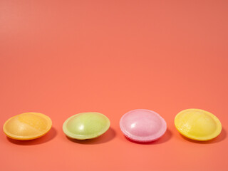 Sweet candies in the shape of a UFO in different colors on a pink background. Flying saucers sugar...