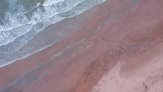 4K aerial view of calm ocean waves and sandy beach in Mandvi, Kutch, India. Top down view over ocean coast. Serene and Tranquil Landscape of beach. Drone moving downwards