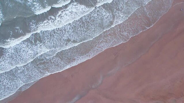 4K aerial view of calm ocean waves and sandy beach in Mandvi, Kutch, India. Top down view over ocean coast. Serene and Tranquil Landscape of beach. Drone moving upwards