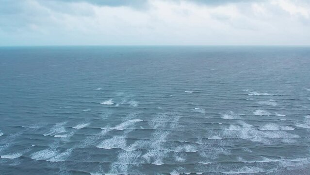 4K aerial shot of Dark clouds over ocean during monsoon season. Ocean waves at Mandvi beach, Kutch, India. Nature landscape. Travel background.