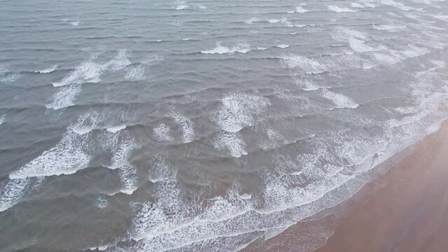 4K aerial view of calm ocean waves and sandy beach in Mandvi, Kutch, India. Top down view over ocean coast. Serene and Tranquil Landscape of beach.
