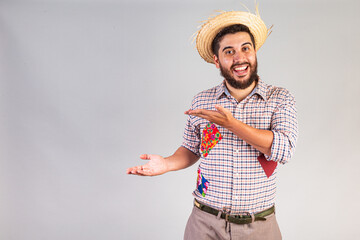 Brazilian man wearing festa junina clothes. Arraial, Feast of Saint John. presenting product or advertisement on the side.