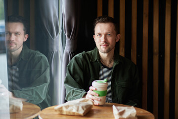 Young man sitting in a cafe on a coffee break. Looking at the camera having good time in a small cafe High quality photo