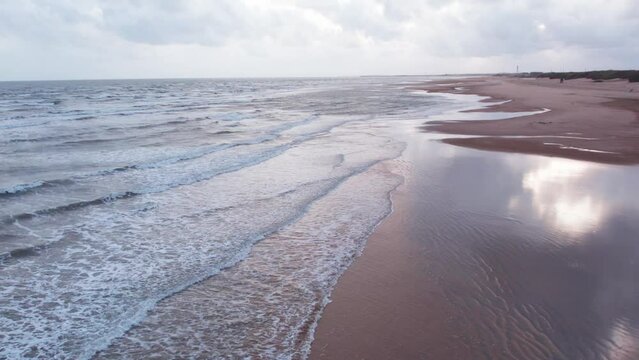 4K Aerial view of tropical sandy beach at Mandvi, Kutch, India. Beach waves and clouds in sky during monsoon season. Bird Eye View 4K Cinematic Drone Footage. Travel and holidays concept.