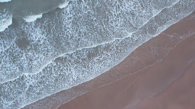 4K Aerial footage of an empty beach with calm ocean waves in Kashi Vishwanath beach in Mandvi, Kutch, Gujarat. Birds eye view drone shot of ocean waves on the sandy beach. Copy space for text
