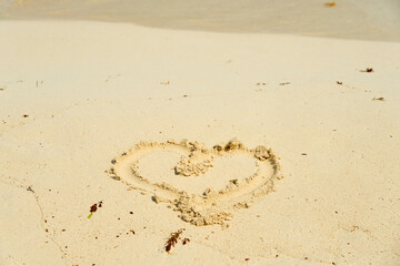 A heart painted on the sand of a tropical beach.