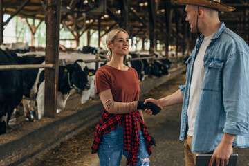 Farmer shakes hands with a female farmer in a stable.