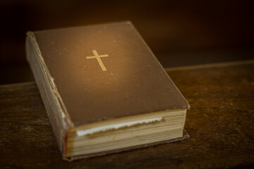 Bible on the church bench. God's word in one little book. Soft selective focus. Artificially created grain for the picture