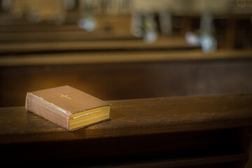 Bible on the church bench. God's word in one little book. Soft selective focus. Artificially...