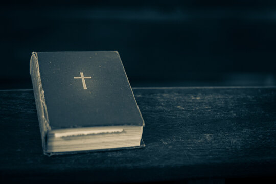 Bible on the church bench. God's word in one little book. Soft selective focus. Artificially created grain for the picture