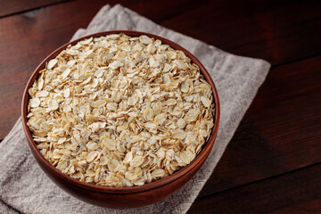 Oat flakes bowl on a linen napkin. Dry rolled oatmeal on wooden boards. Vegan food concept. Copy space