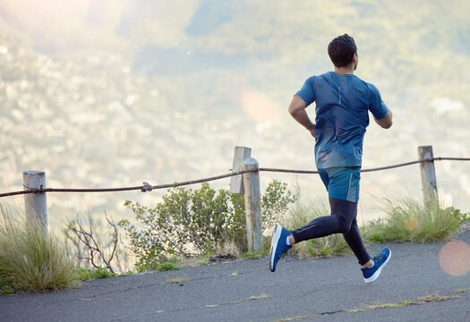 Man running in road, fitness and cardio outdoor, exercise and healthy, active lifestyle with back. Male runner on path to run, train for marathon with speed, energy and workout for health and sport