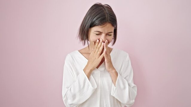 Young beautiful hispanic woman smiling confident sneezing over isolated pink background