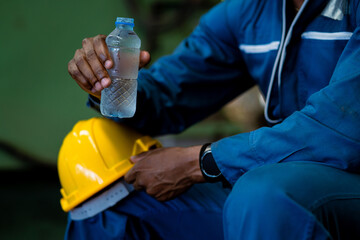 Worker drinking water from bottle during work break. Stay hydrated at work.