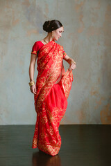 Pregnant woman in red sari. mehendi. Indian painting on woman's hands and pregnant belly with henna tattoo on room background
