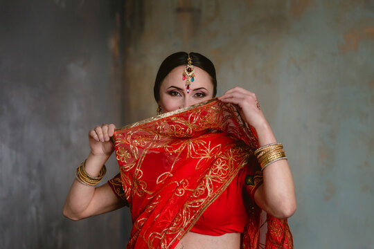 Pregnant woman in red sari. mehendi. Indian painting on woman's hands and pregnant belly with henna tattoo on room background