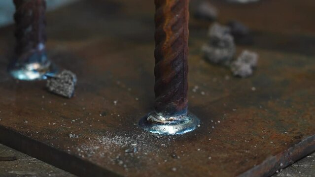 A worker removes slag after welding plates and reinforcement