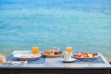 Delicious breakfast on coast, surrounded by the stunning views of the beach. Variety of fresh food on set table at luxury seaside restaurant.