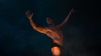 Naklejka premium A muscular athlete in an epic pose arms outstretched, fog and smoke on the background, warm mystical light from below, the concept of the antique beauty of the human body
