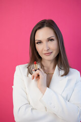 Elegant brunette with red lipstick, makeup. Minimalistic portrait on pink