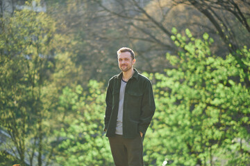 Young man smiling confident standing at park in the sunlight looking at the camera. High quality photo