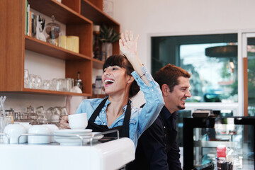 Smiling Caucasian Young barista or businesswoman is wearing apron and working in the coffee shop. She is greeting and chatting with customers. Start up for small cafe business concept.