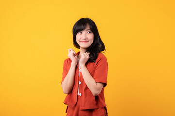 Portrait beautiful young asian woman cute and shy dressed in orange clothes isolated on yellow studio background.