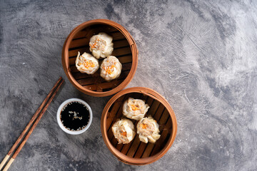 Chinese steamed dumplings or  Dim Sum in bamboo steamer on dark abstract background