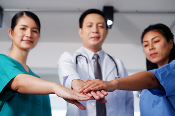 Asian chief physician man is holding hand with surgeon doctor women wears blue and green surgical...