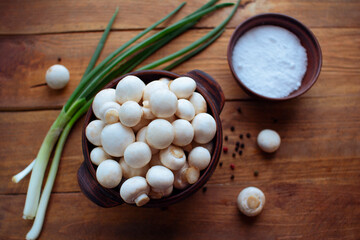 
Champignon mushrooms in a bowl on wooden table. Organic food ingredients.
