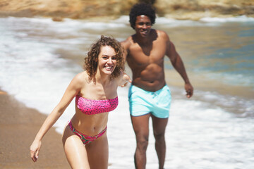 Joyful multiracial couple fooling around on beach