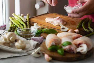 Male hands salting fresh pieces of chicken thigh meat on wooden cutting board. Recipe for cooking...